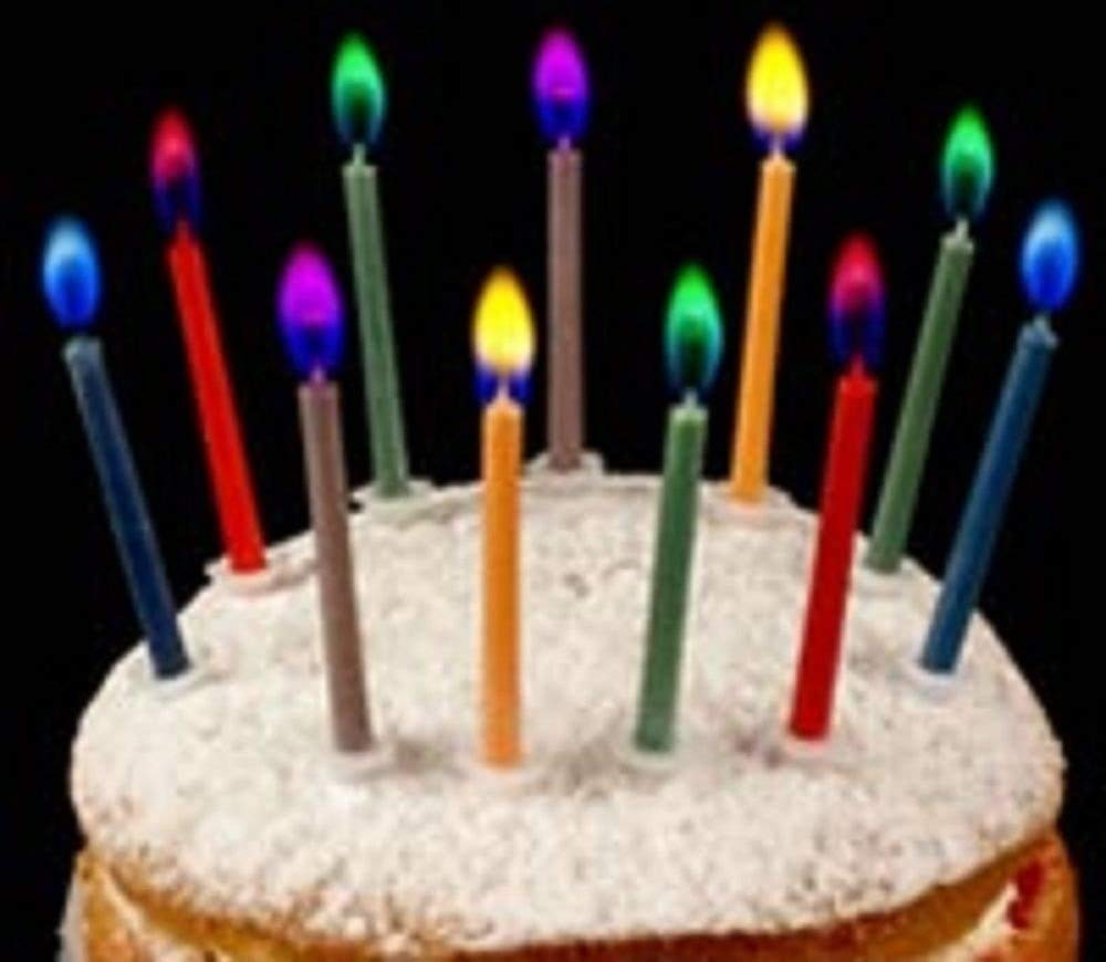 Coloured birthday cake candles with multicoloured flames on a frosted cake